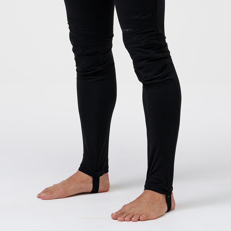 Black NordicHeat warm clothing, designed as long underwear with foot straps, is shown on a person in neutral studio.