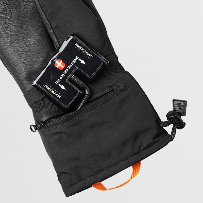 Black glove with opened pocket showing inserted NordicHeat battery pack. Text on battery pack: "This way into the pocket" and "NORDICHEAT" with arrow, accompanied by Danish flag.