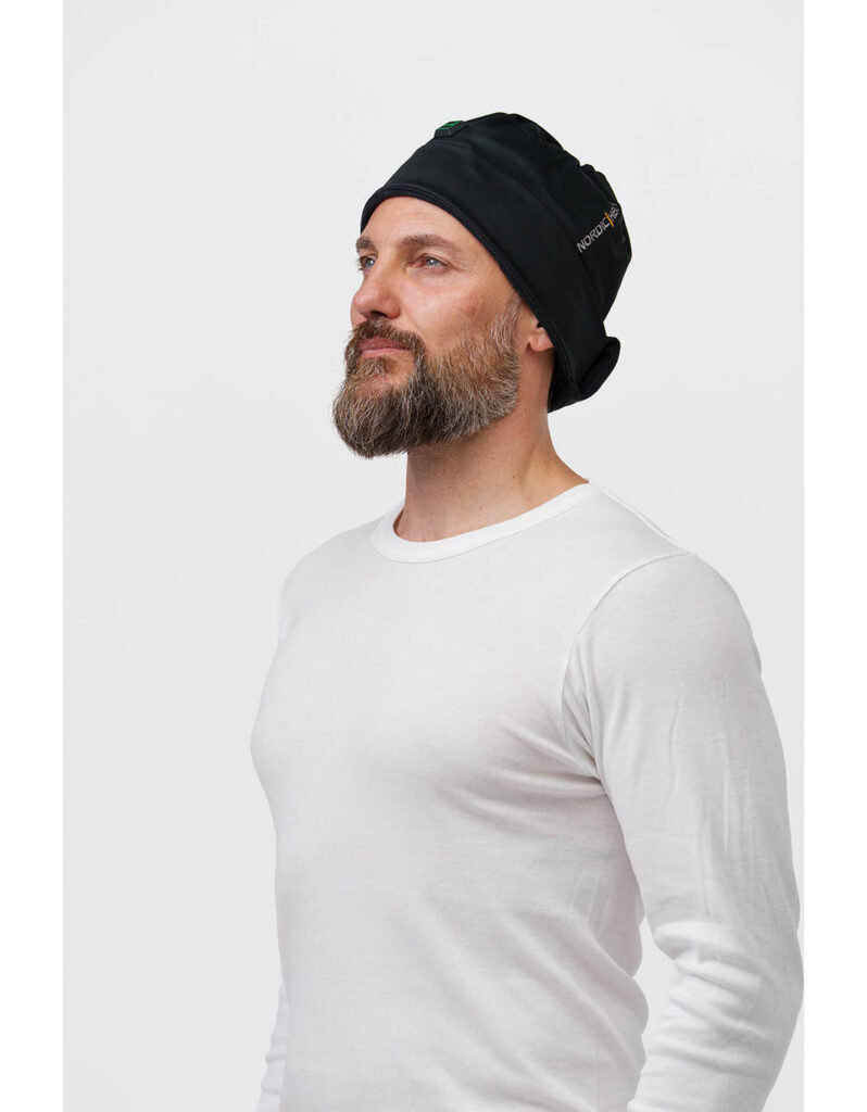 A person wears a black NordicHeat warming cap, ideal for an active lifestyle in cold weather. Visible text: "NORDICHEAT".