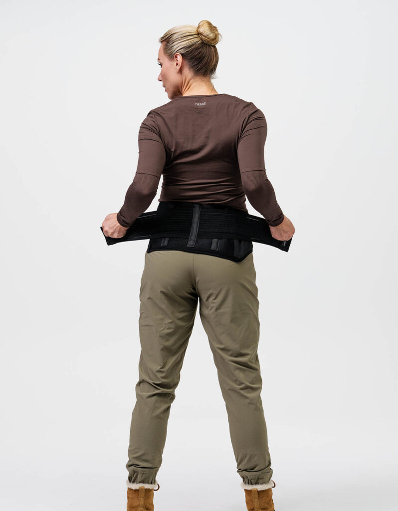 A woman wearing comfortable warm clothing is seen adjusting a belt for extra support, promoting the NordicHeat active lifestyle concept. Text on the garment: "casall".