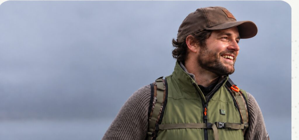 A person wearing a khaki jacket and cap laughs outside in foggy weather, suggesting an active lifestyle with NordicHeats warm clothing. No visible text.